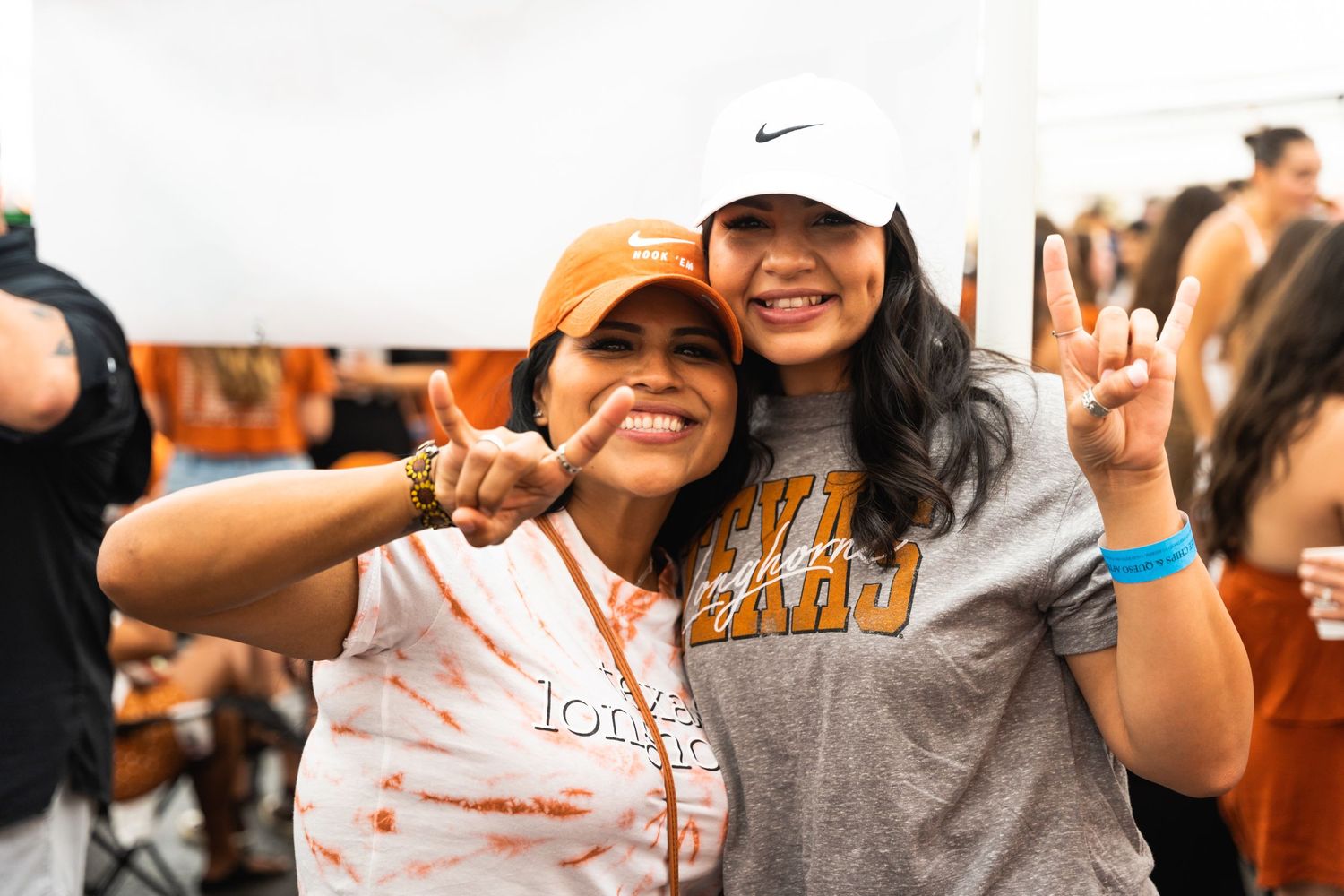 Friends celebrate at outdoor tailgate party wearing college spirit gear.