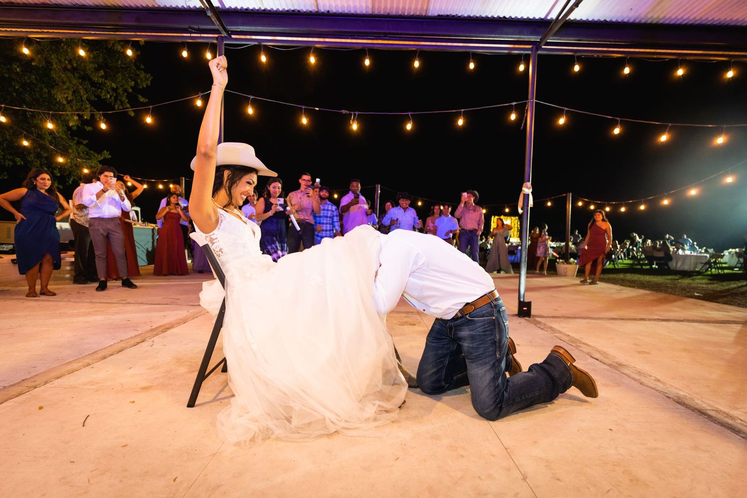 A dramatic dip during a wedding dance on an outdoor patio under string lights.