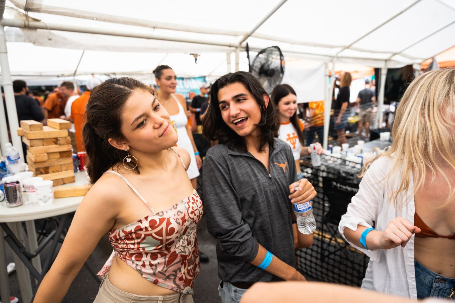 Friends chatting and having fun at a summer party under a white tent.