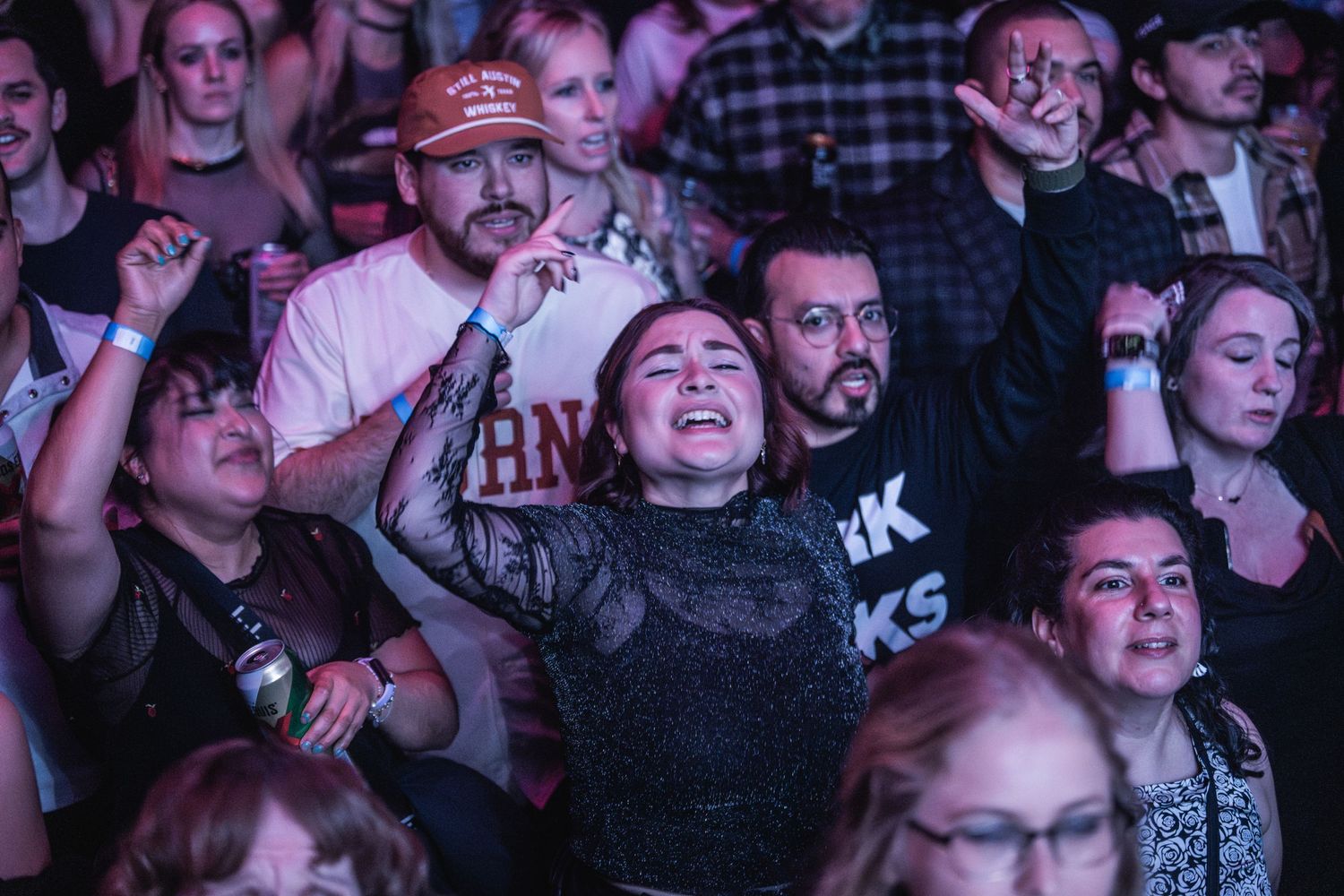 Passionate fans reacting to music at a dimly lit concert venue.