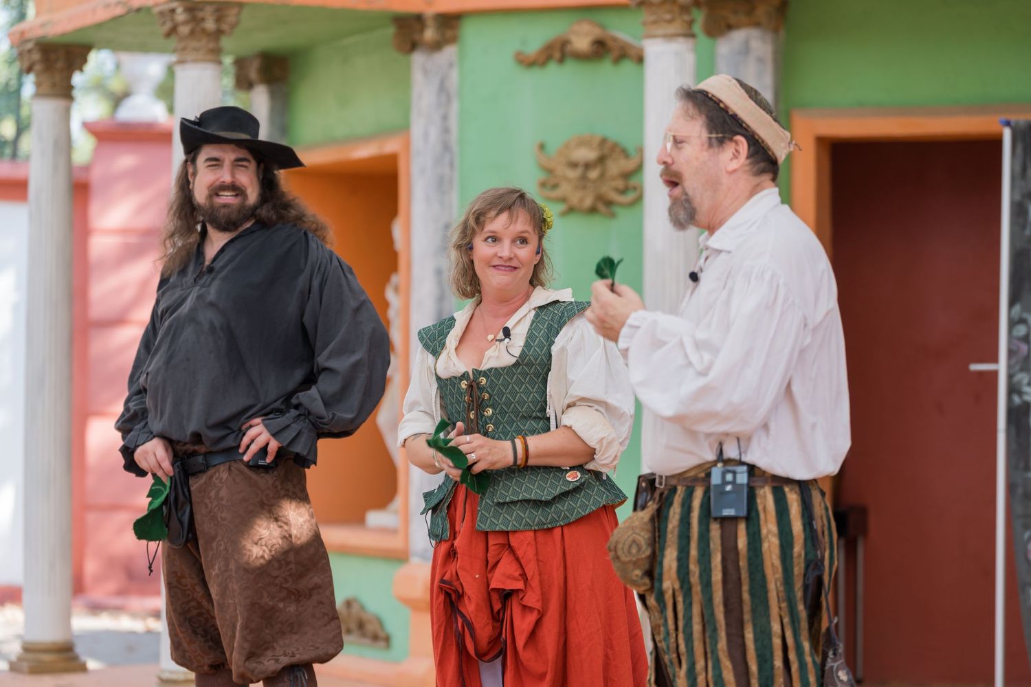 Performers in renaissance fair costumes interacting during an outdoor show.