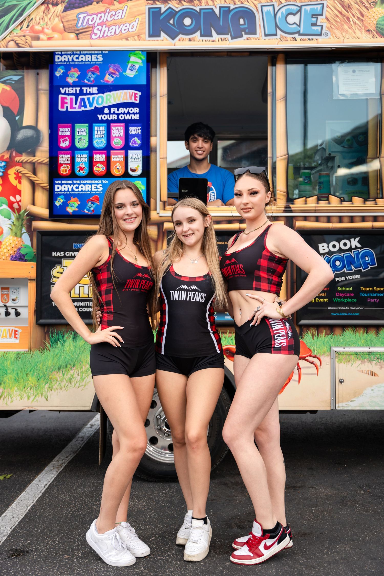 Food truck staff pose together outside tropical Kona Ice stand wearing coordinated outfits.