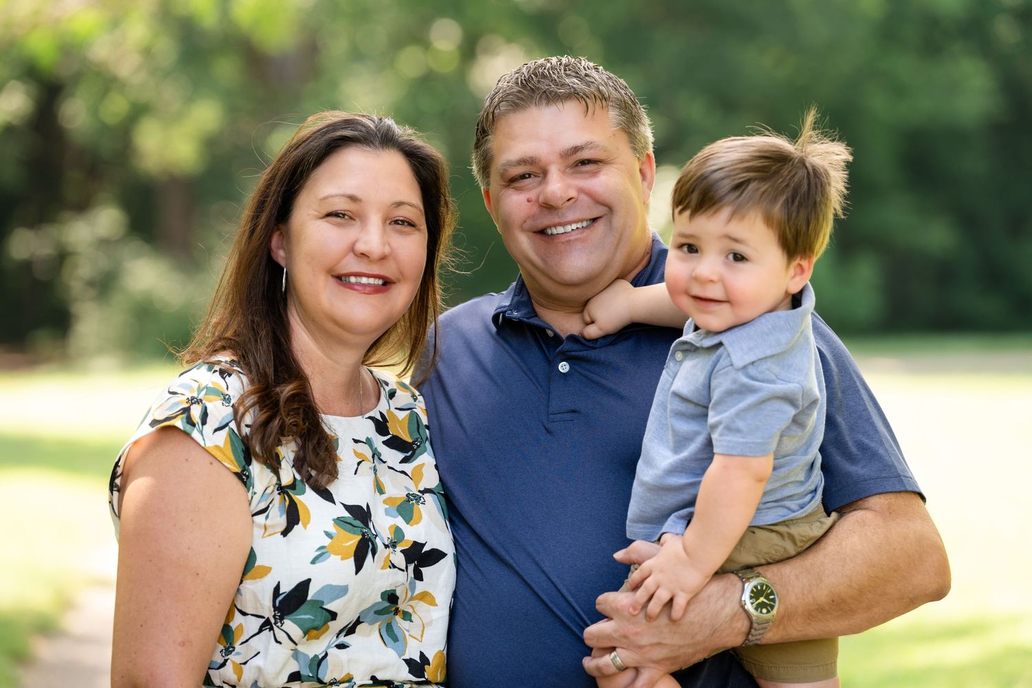 A heartwarming family portrait outdoors with natural summer lighting.