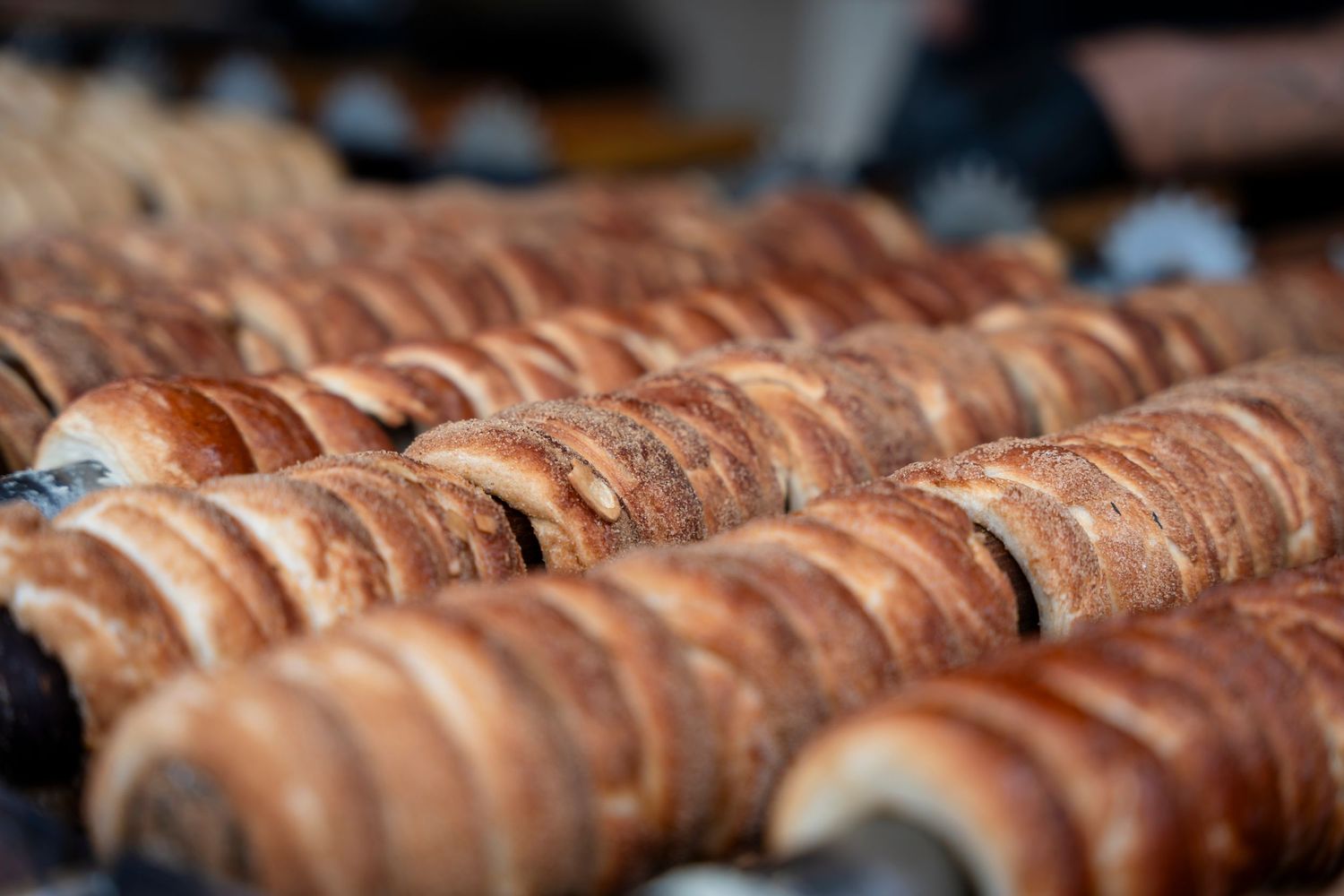 Fresh sausages cooking on a large commercial grill at an outdoor event or festival.