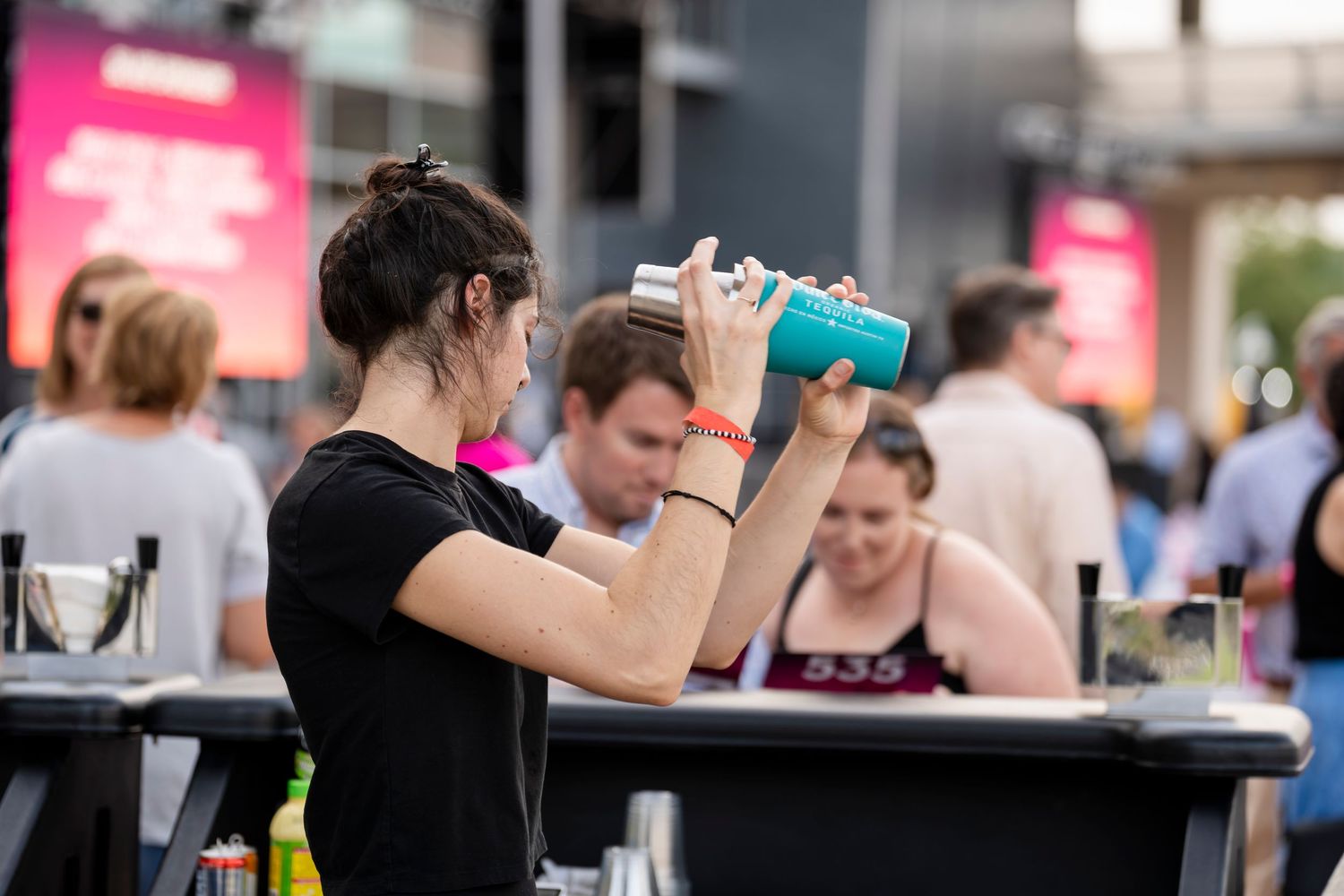 Bartender pouring drinks at a busy bar counter during a crowded evening service.