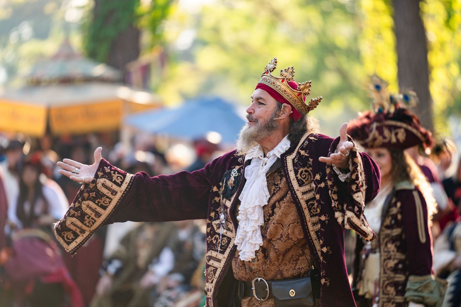 Performers in medieval costumes dance and entertain visitors at a Renaissance festival.