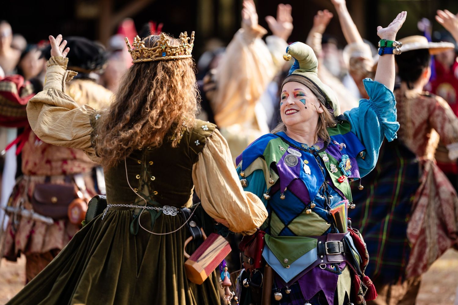 Medieval festival performers dance and celebrate in traditional period costumes at a Renaissance faire event.