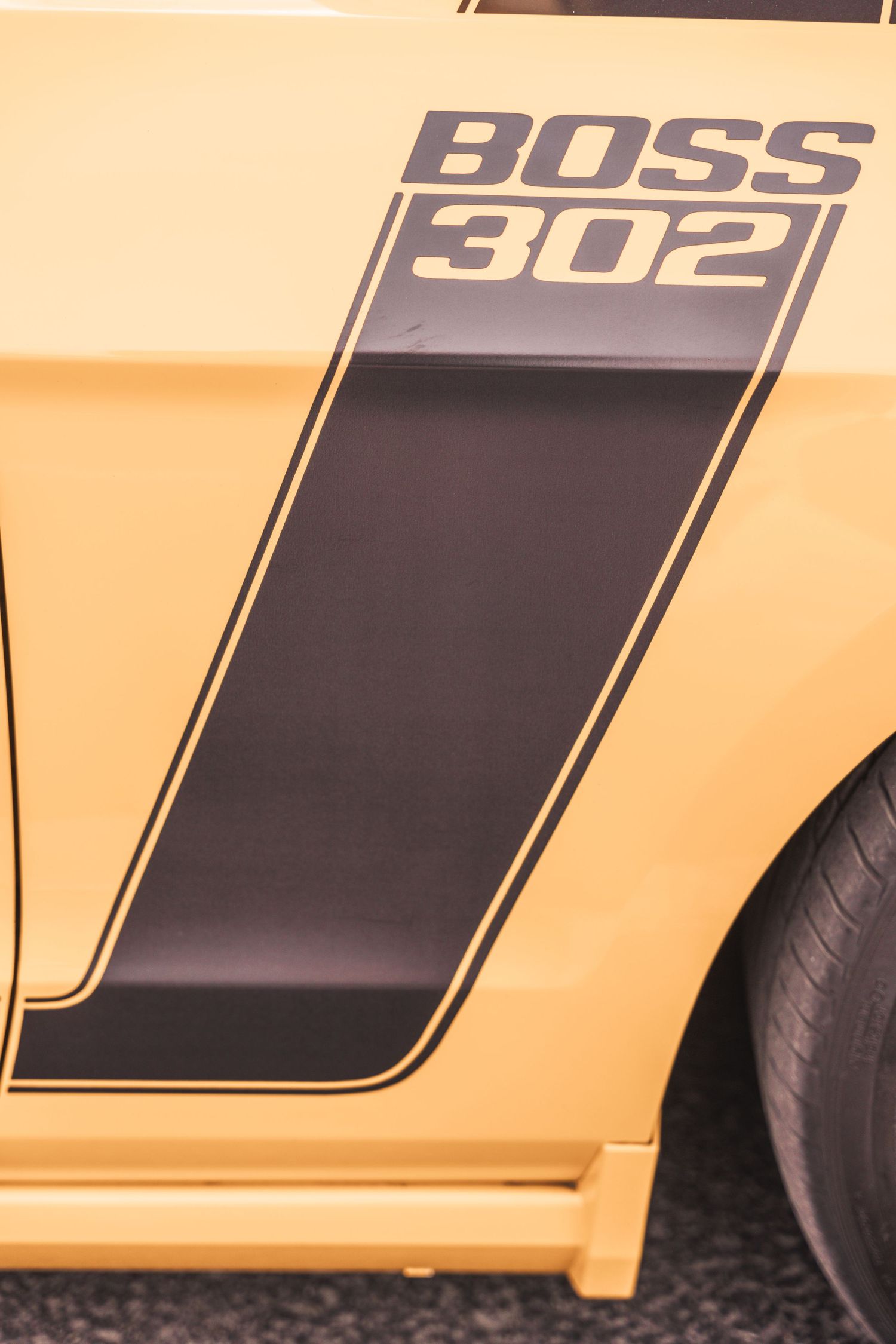 Close up detail of a yellow and black Boss 302 stripe decal on a muscle car.