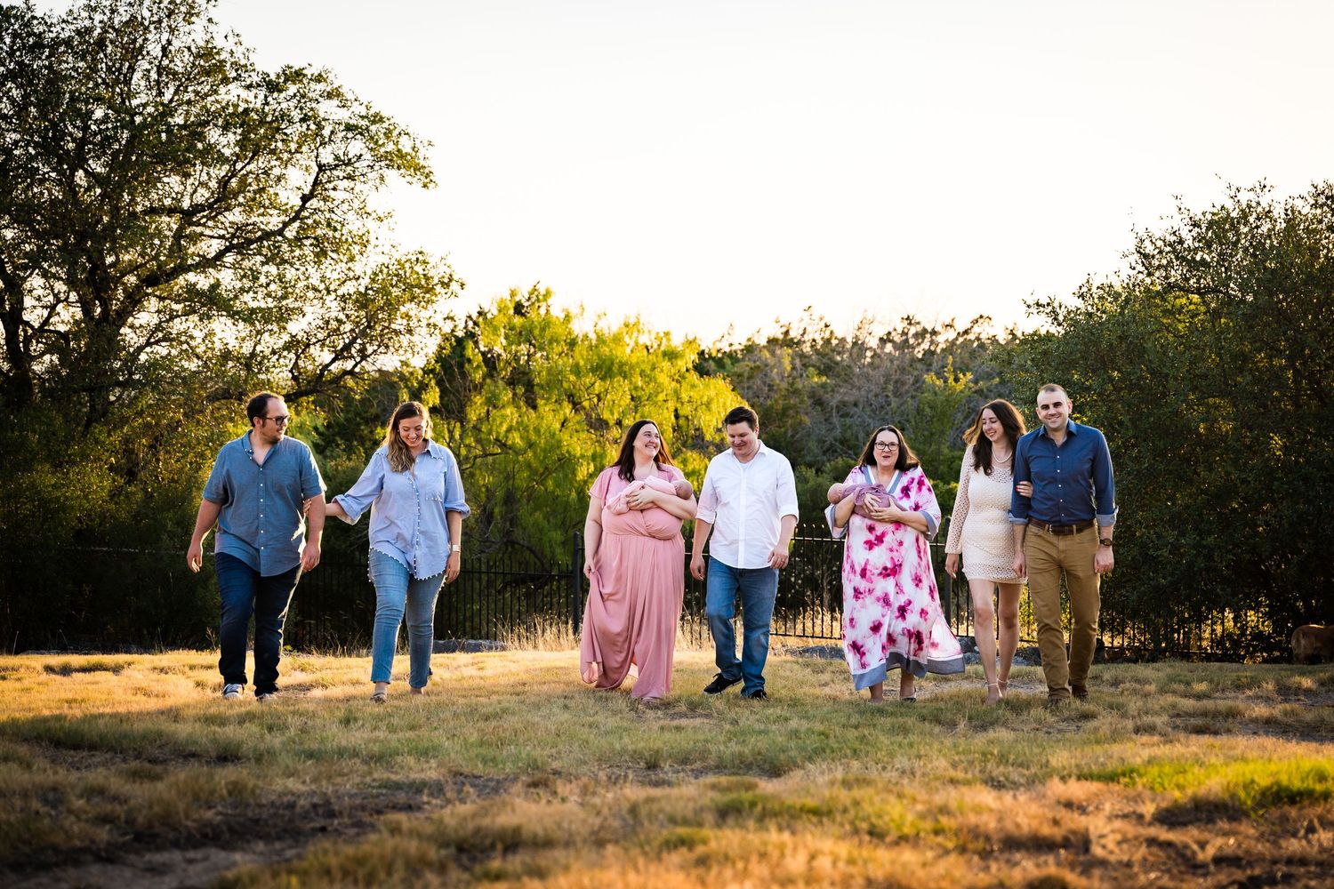 Group walking together on nature trail at sunset with their dog.