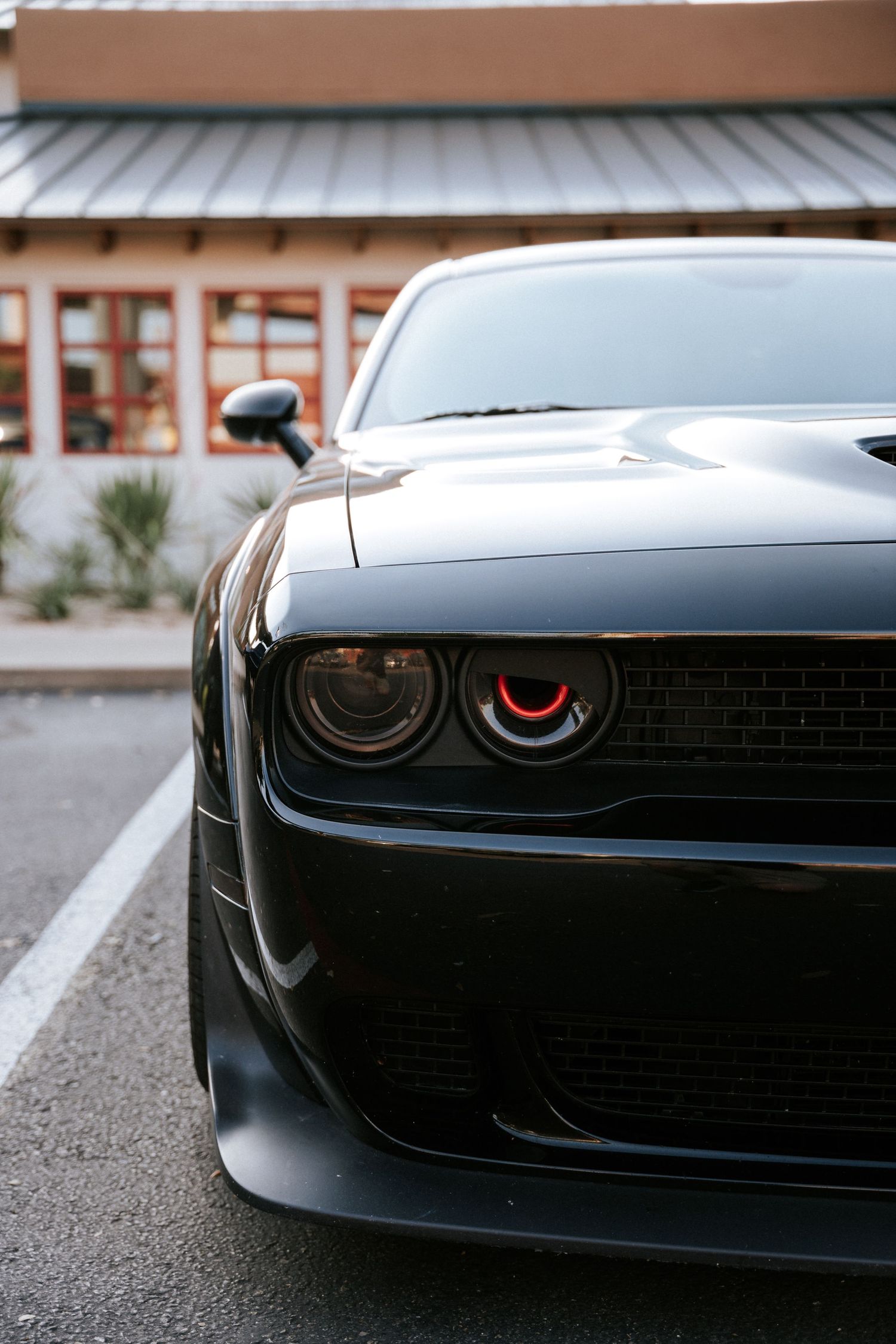 Close-up front view of a black Dodge Challenger with menacing red-accented headlights.
