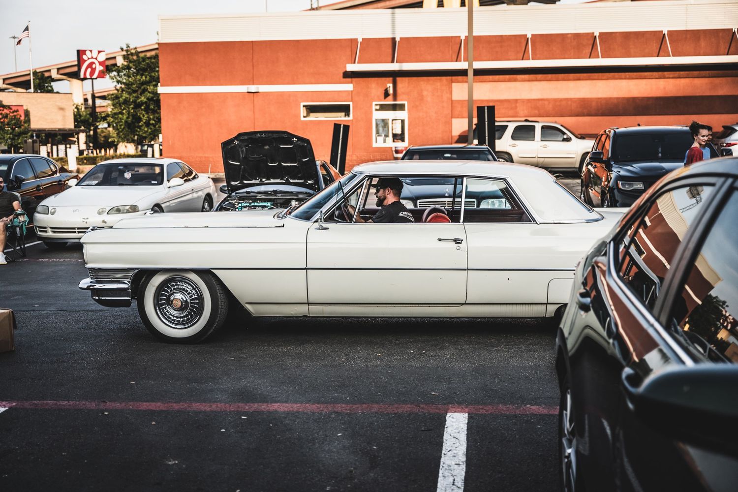 Classic white Cadillac parked in lot among other vintage vehicles.