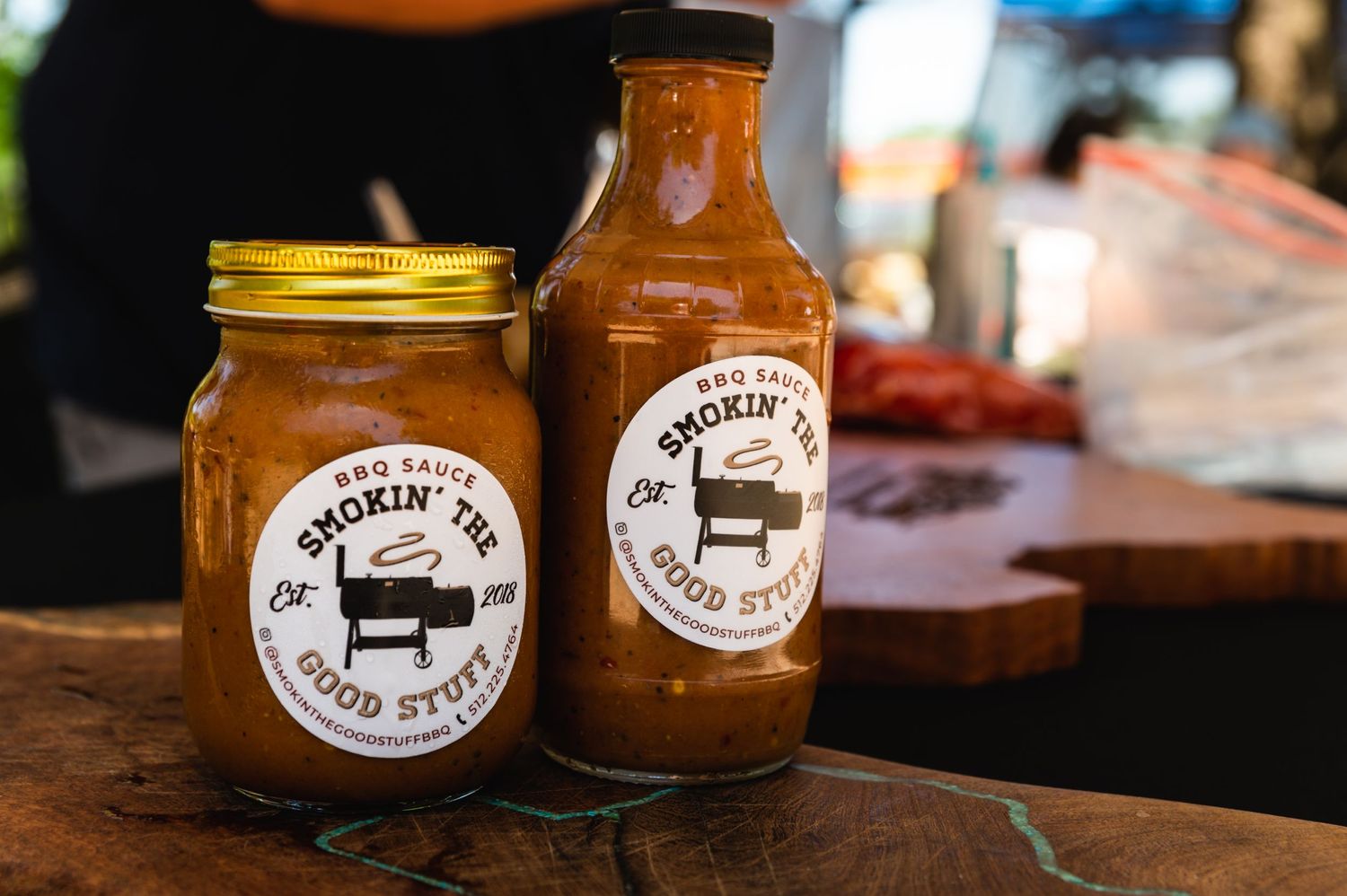 Two glass bottles of artisanal BBQ sauce with matching branded labels.