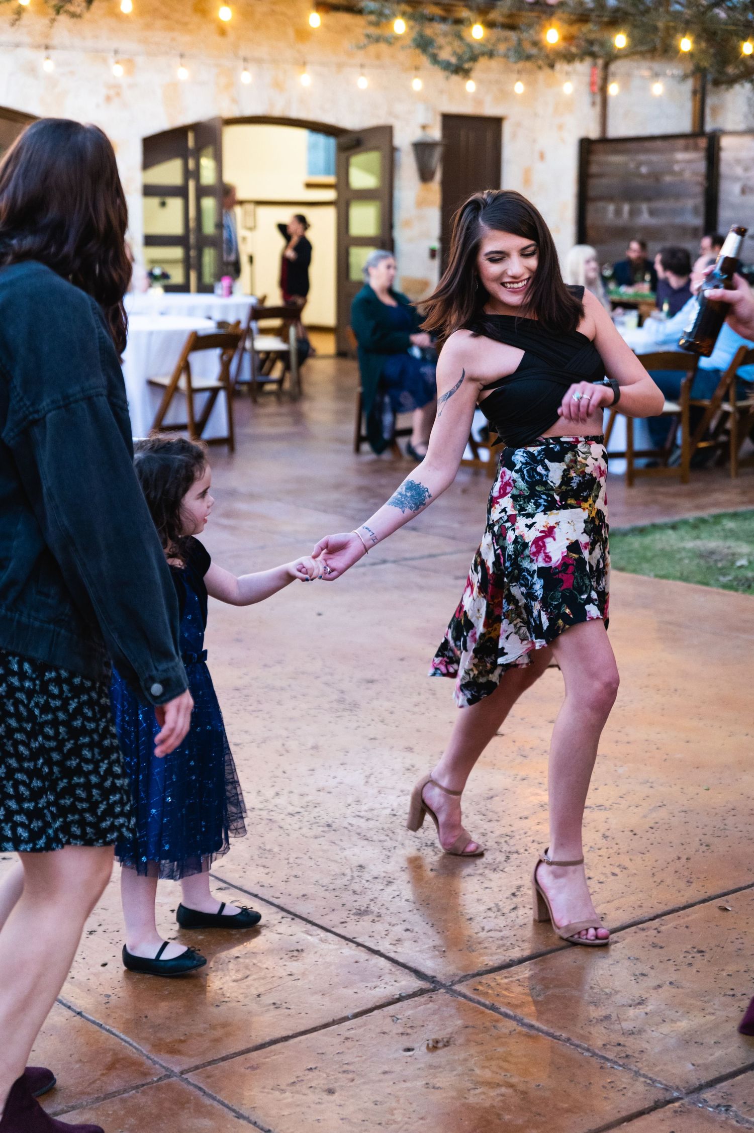 Wedding guests dancing and having fun on an outdoor dance floor with string lights.
