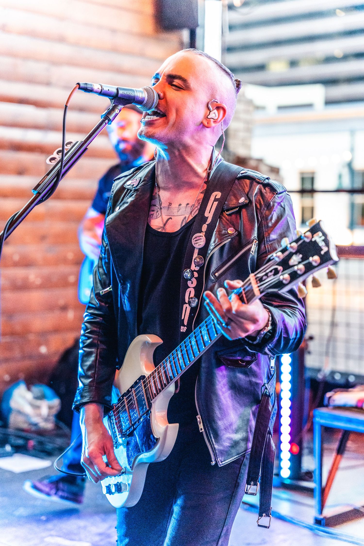 Musician performs with electric guitar under dramatic stage lighting.