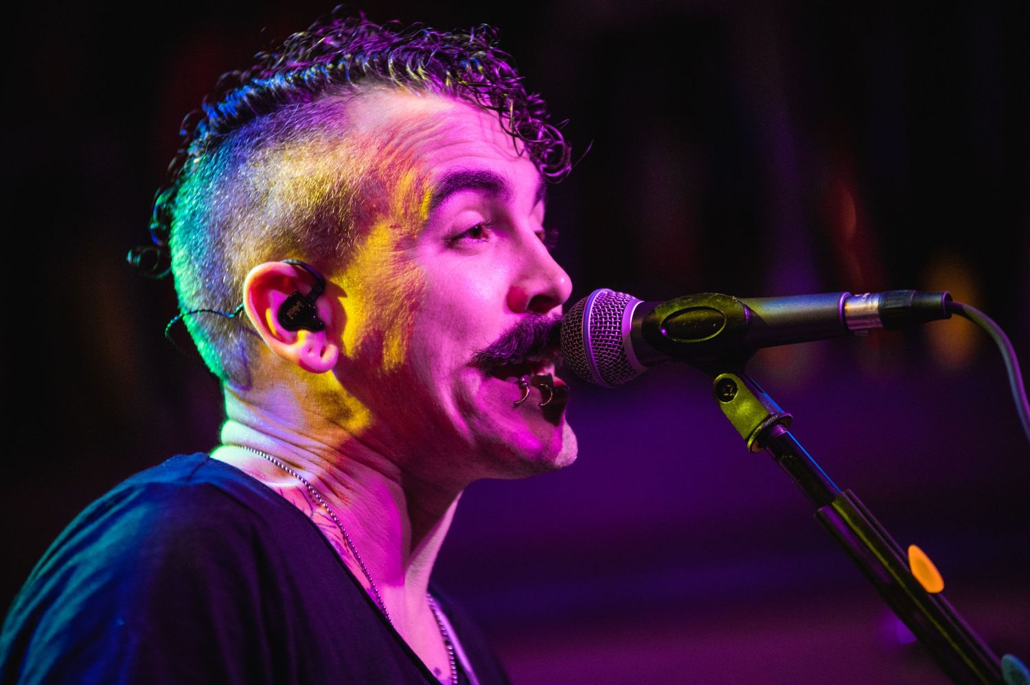 Passionate vocalist performs under dramatic purple and blue stage lighting.