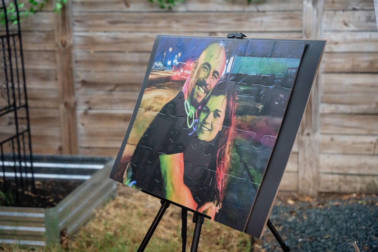 Colorful artwork displayed on easel against wooden fence backdrop.