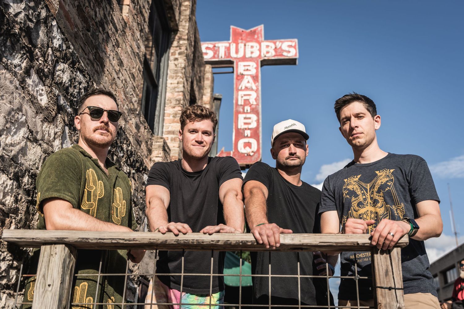Musicians posing in front of iconic Stubb's BBQ neon sign in Austin.