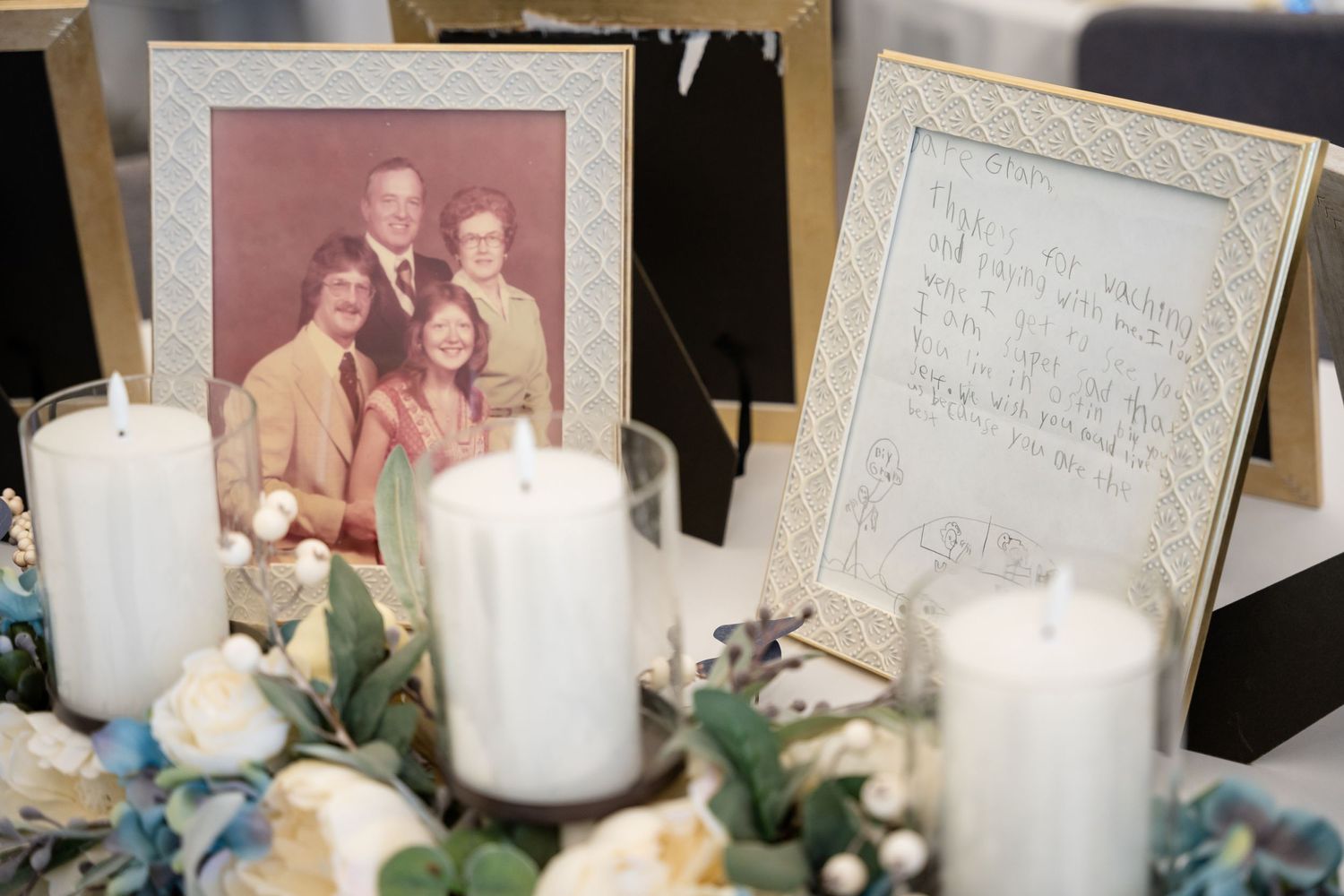 Vintage photograph display surrounded by white pillar candles and floral decorations.