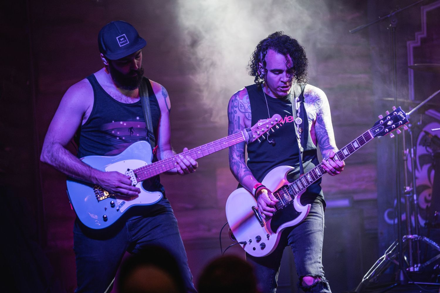 Two guitarists perform together on stage with dramatic lighting effects.