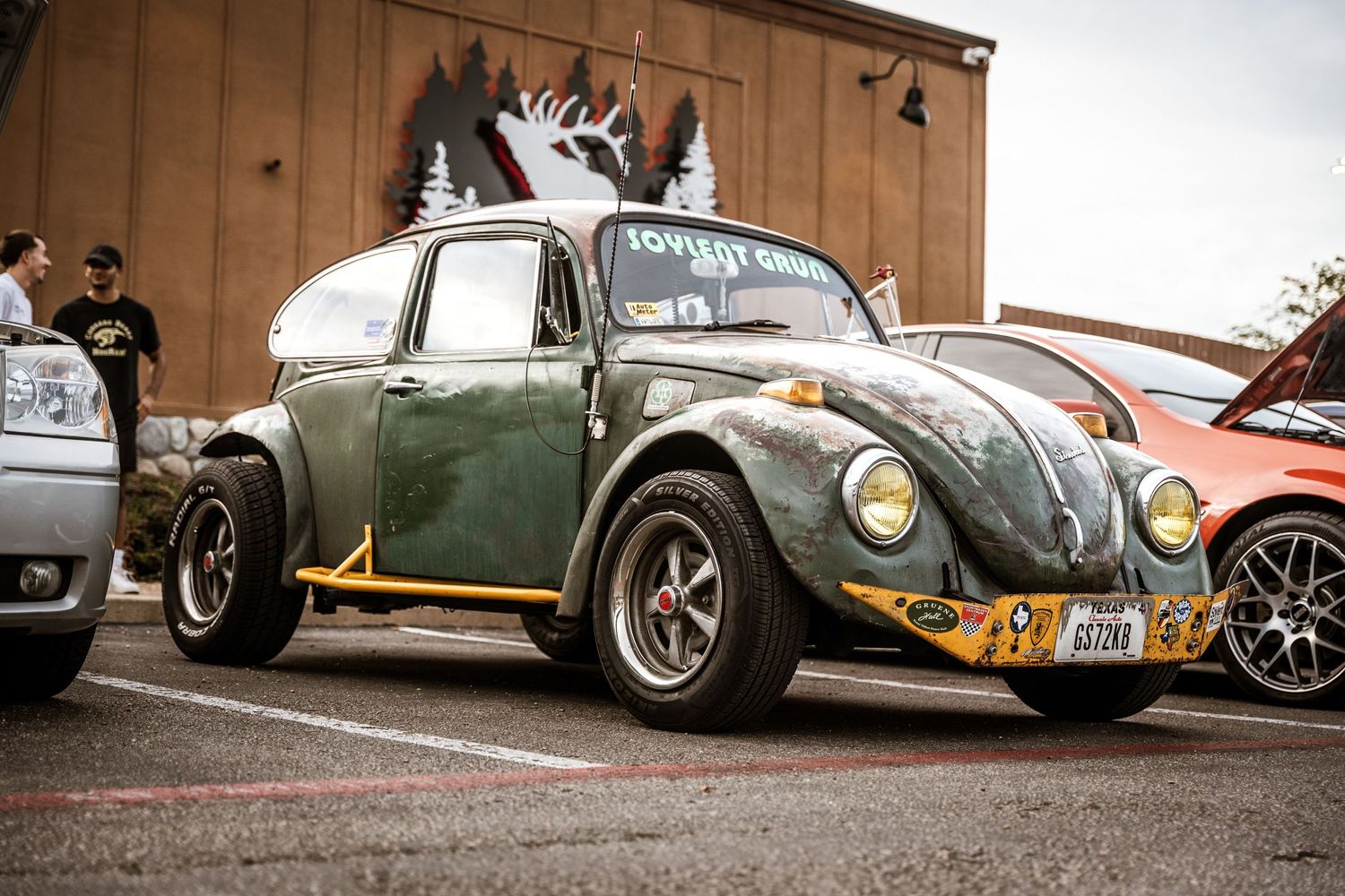 Modified vintage Volkswagen Beetle in green with roof rack at a car show.
