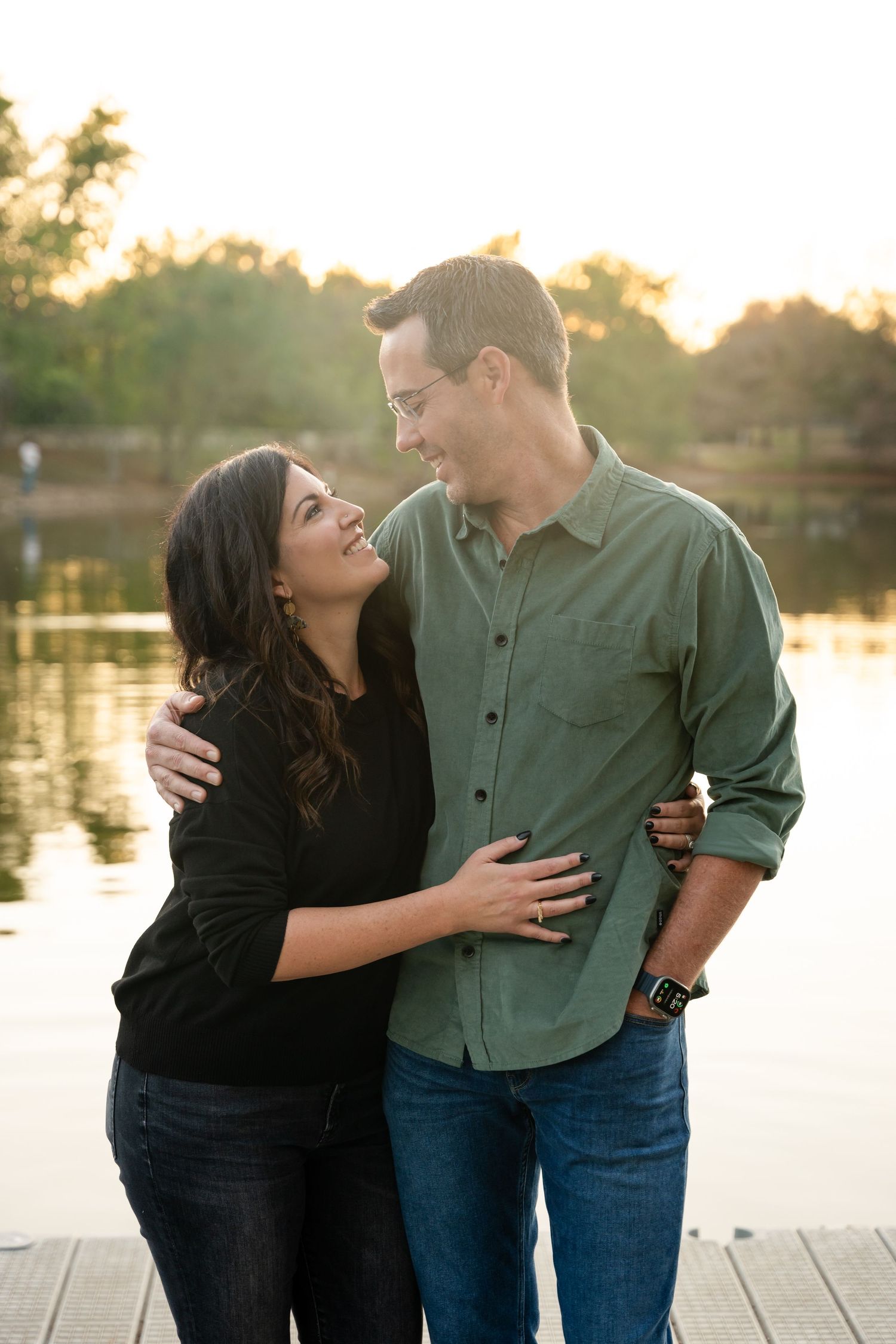 A romantic couple shares a tender moment on a dock at sunset.