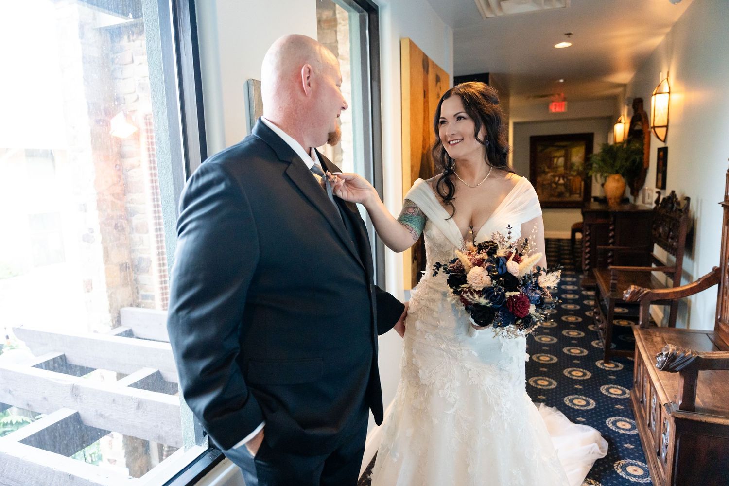 An intimate wedding moment shared between a couple by large windows.