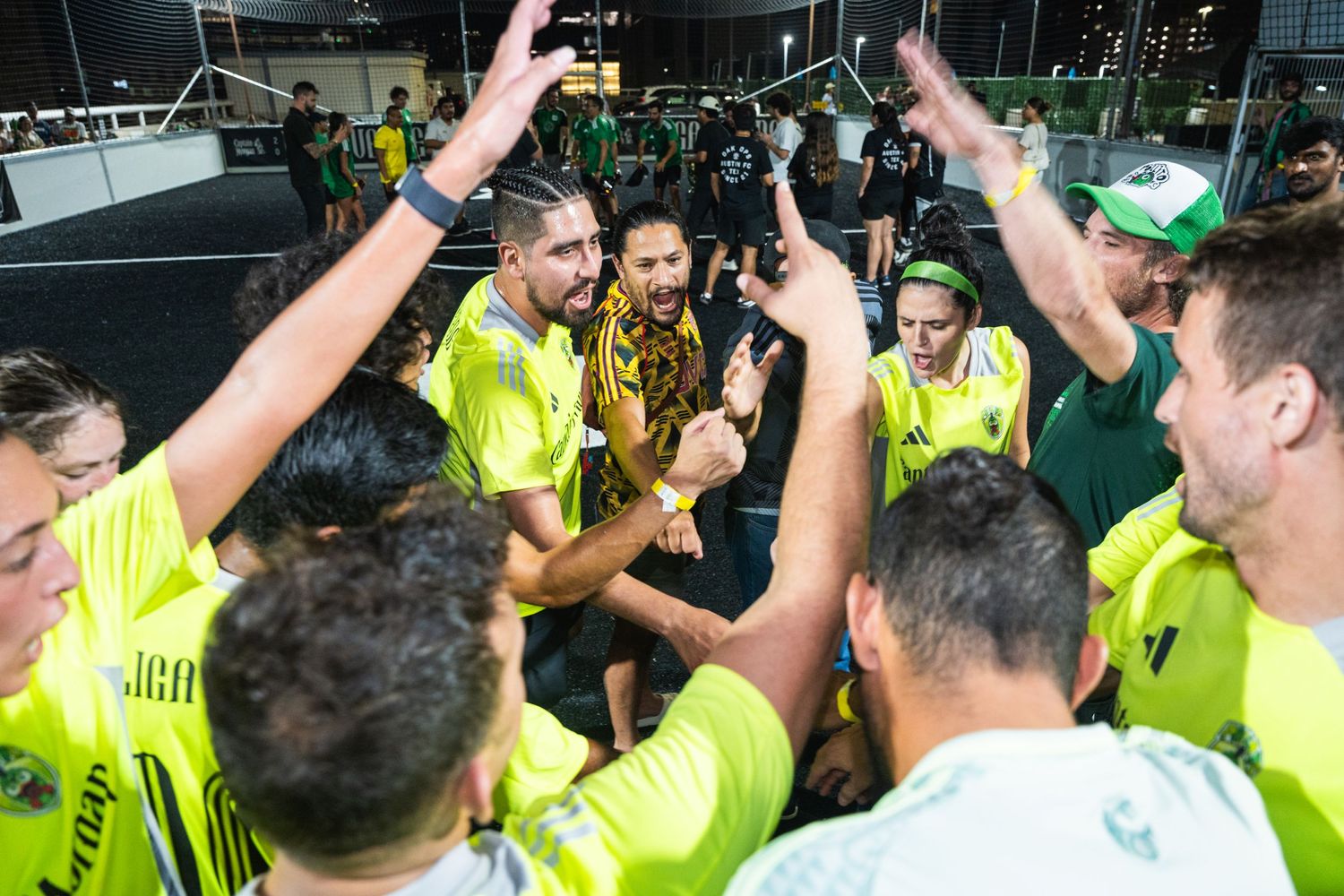 Sports team celebrates victory by raising trophy in team huddle.