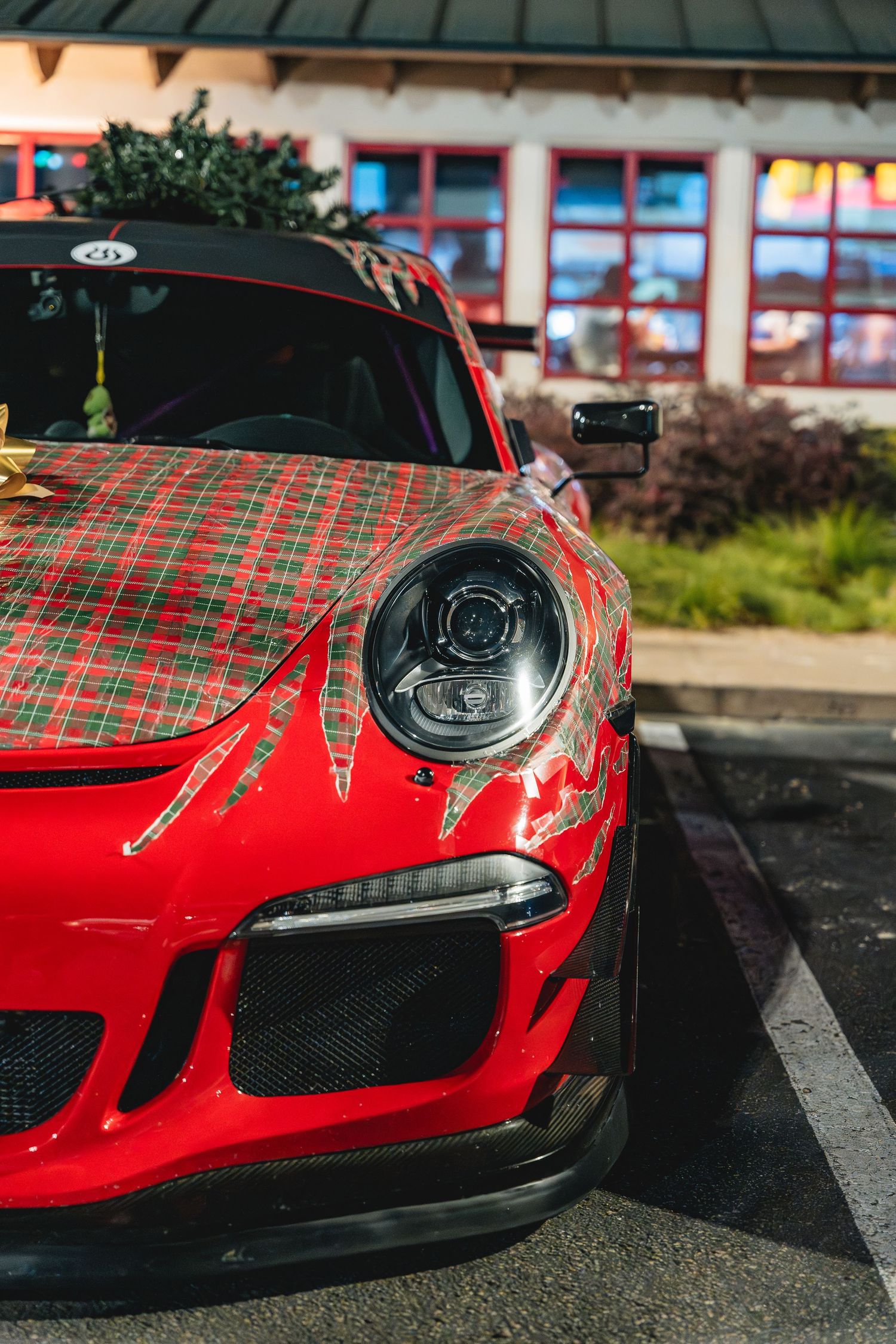Close up of a red Porsche GT3 with plaid wrap detail showing the distinctive headlight design.