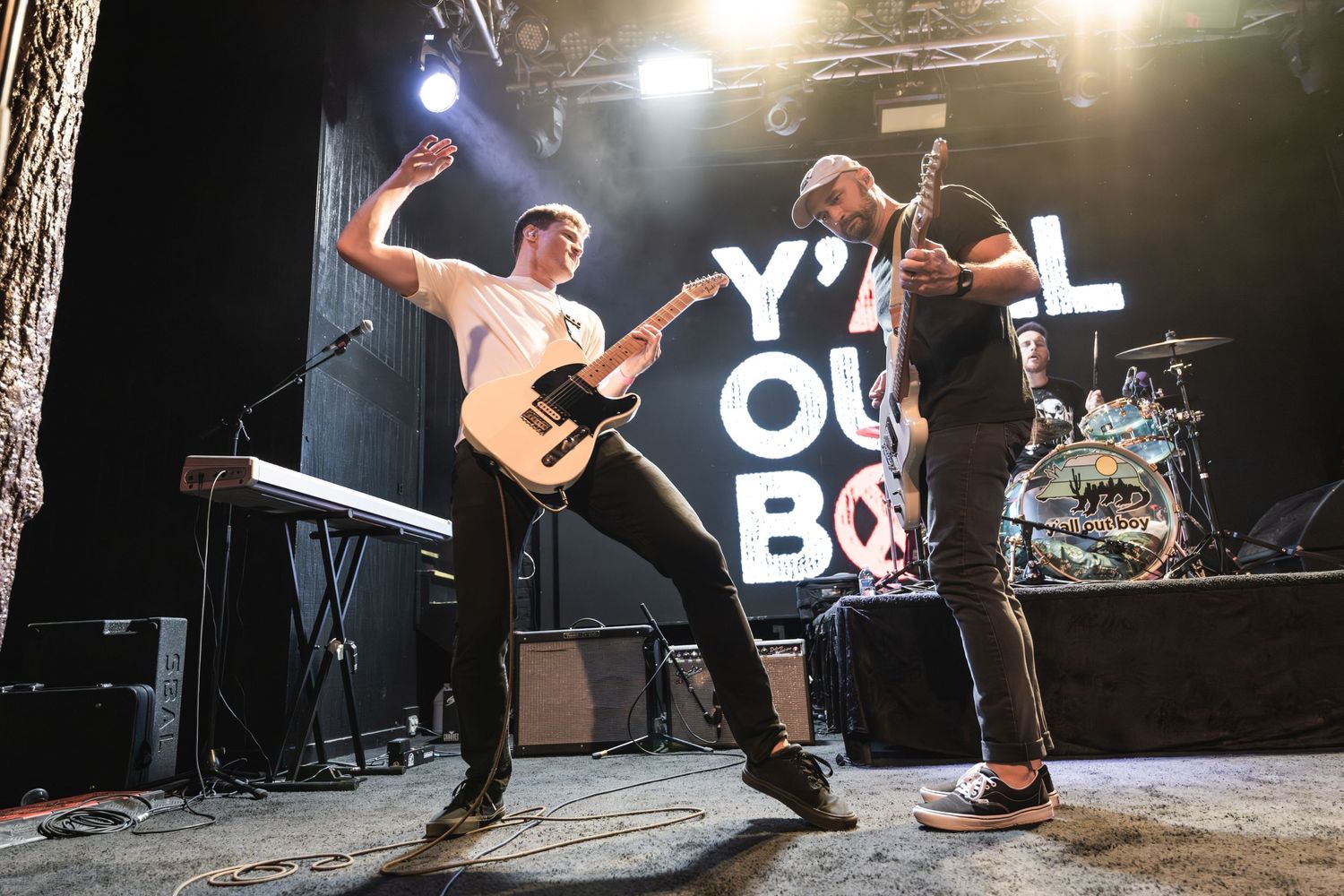 Musicians performing with high energy on concert stage with band name visible in background.