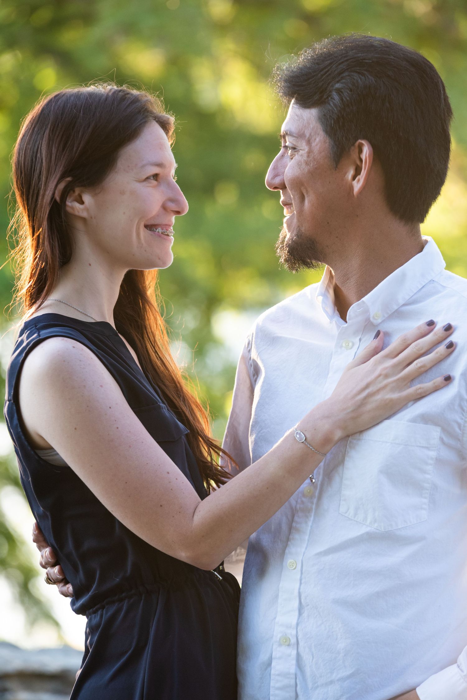 An intimate engagement portrait with soft golden hour lighting in the background.