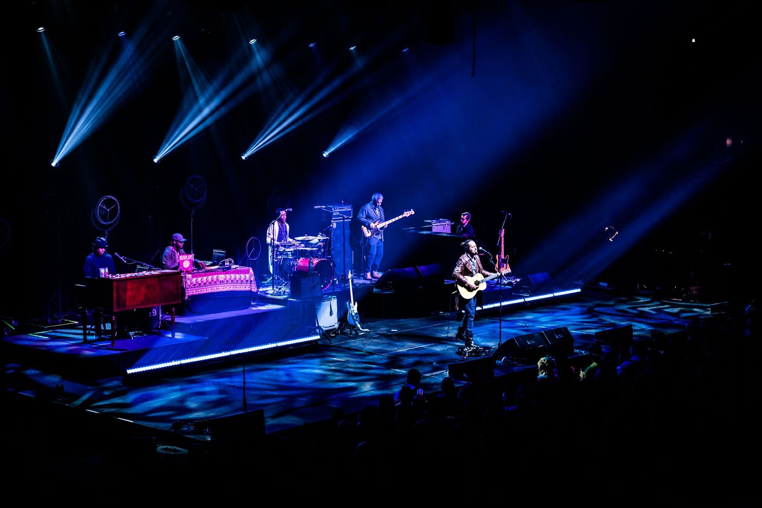 Band performs on stage with dramatic blue spotlights creating atmospheric concert lighting.
