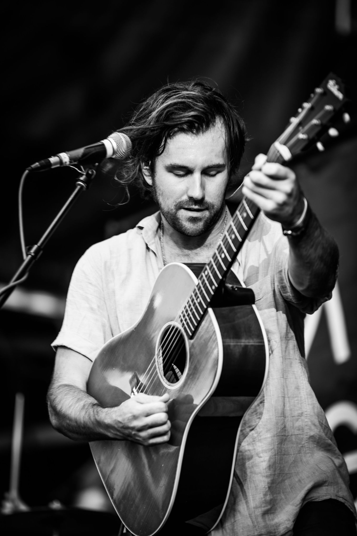 Artist performing with acoustic guitar in black and white shot.