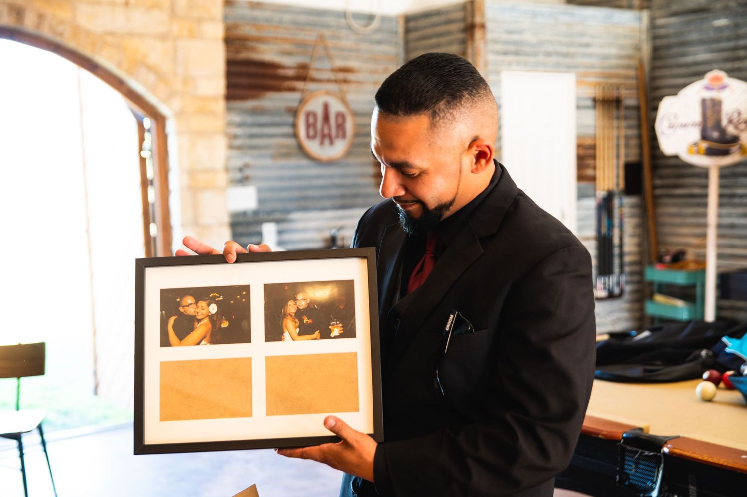 A person in formal attire looks at photos in a picture frame.