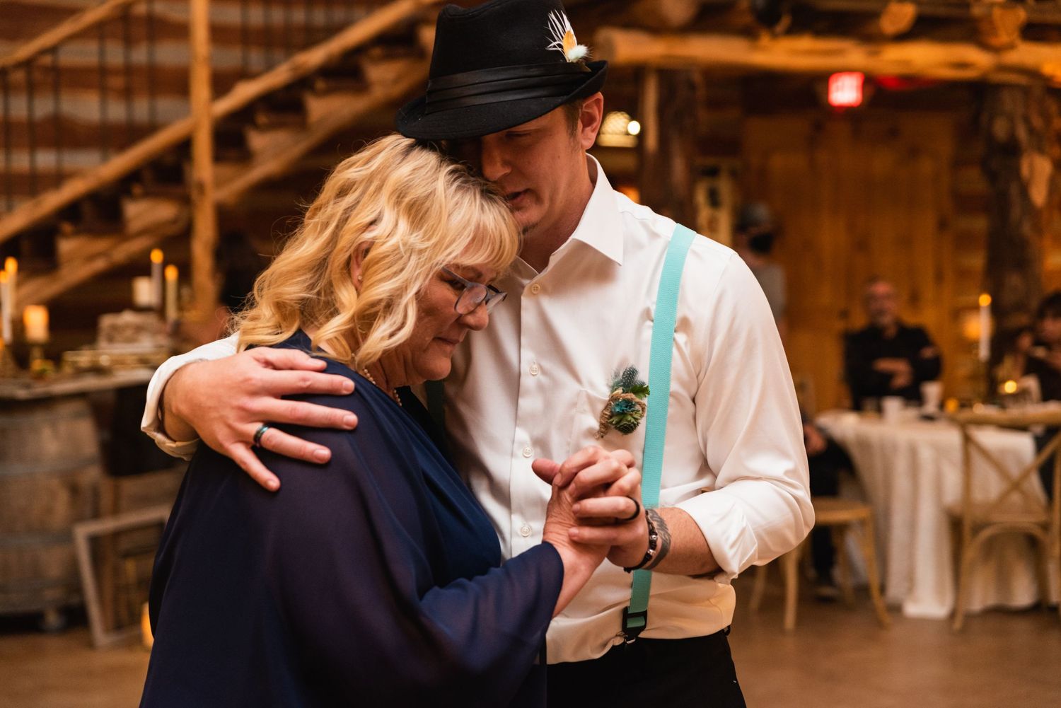 Two people share an intimate dance moment at a rustic barn wedding reception.