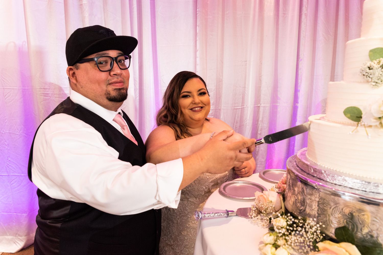 Newlyweds cutting their wedding cake together at the reception.