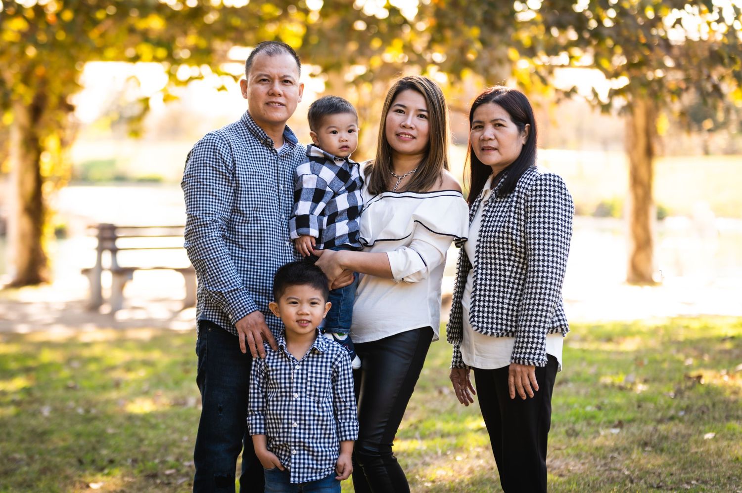 A family portrait of five people standing together outdoors in coordinated outfits.