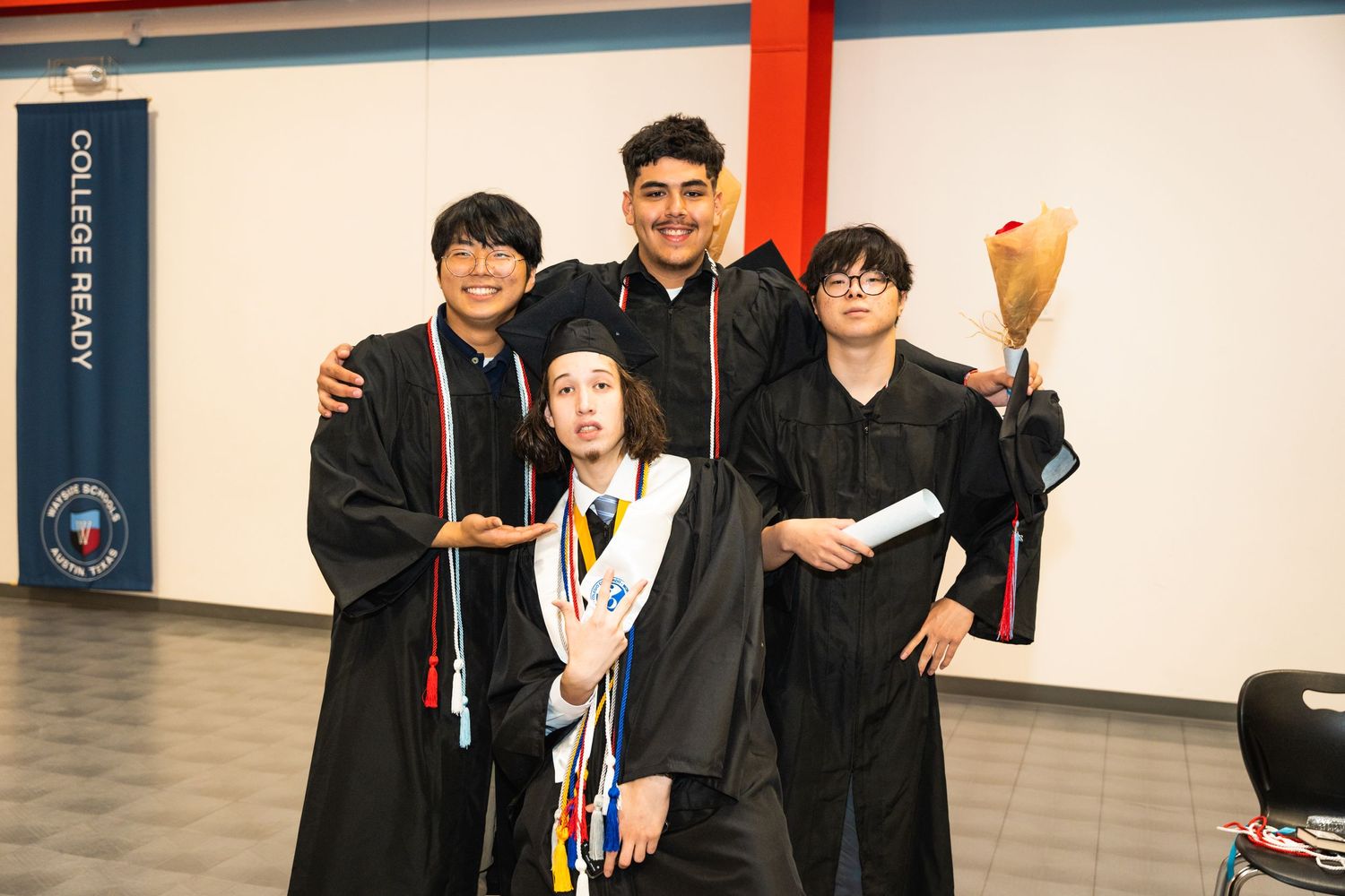 A group of graduates in black robes celebrating together after commencement.