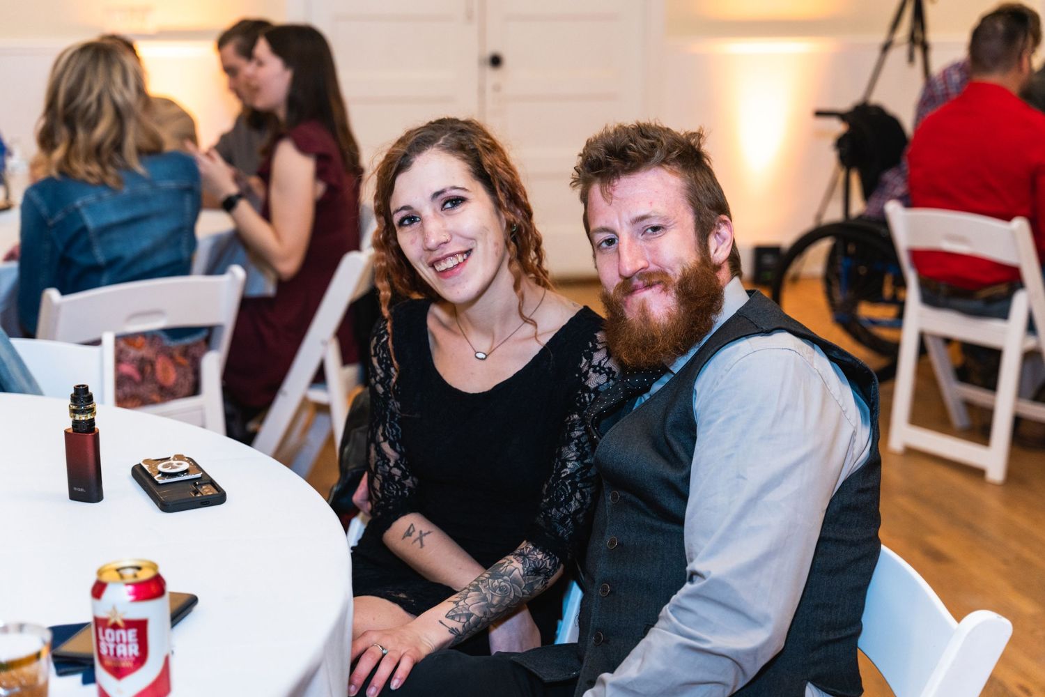 Wedding guests enjoy the reception while seated at tables with drinks and decorations.