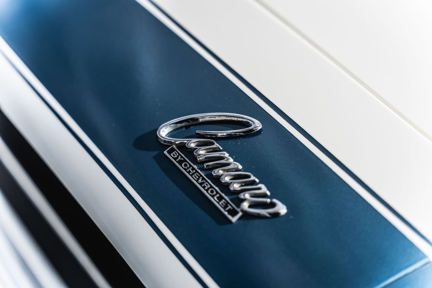Close-up detail shot of blue Camaro badge on classic car exterior.