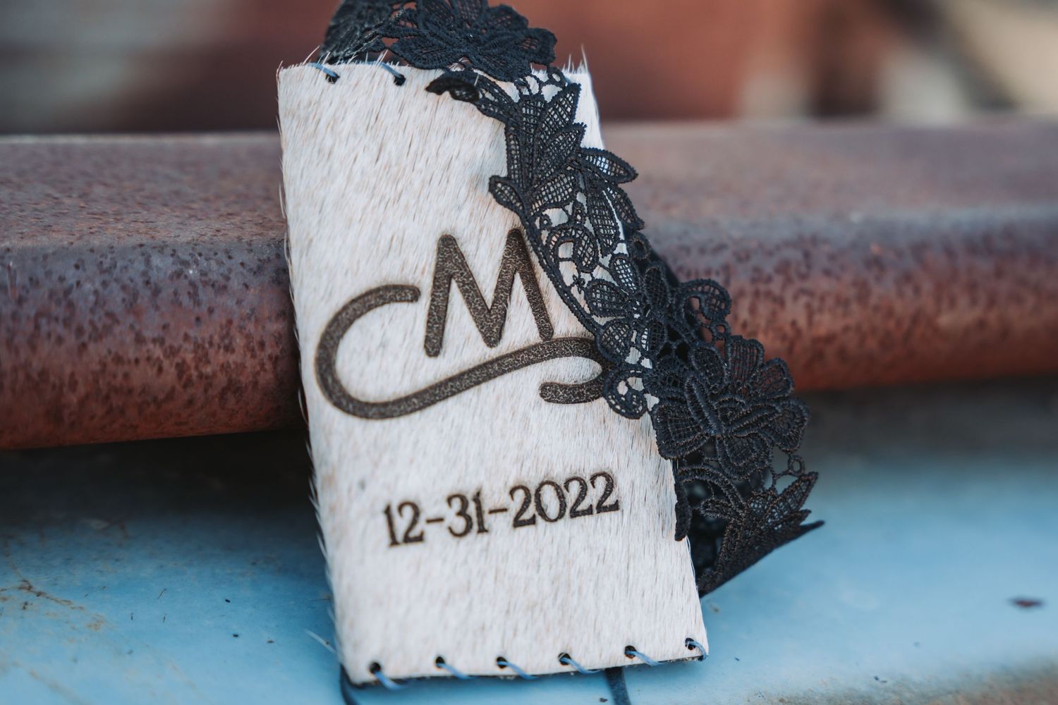 Custom leather wedding date tag with black lace trim reading CM 12-31-2022.