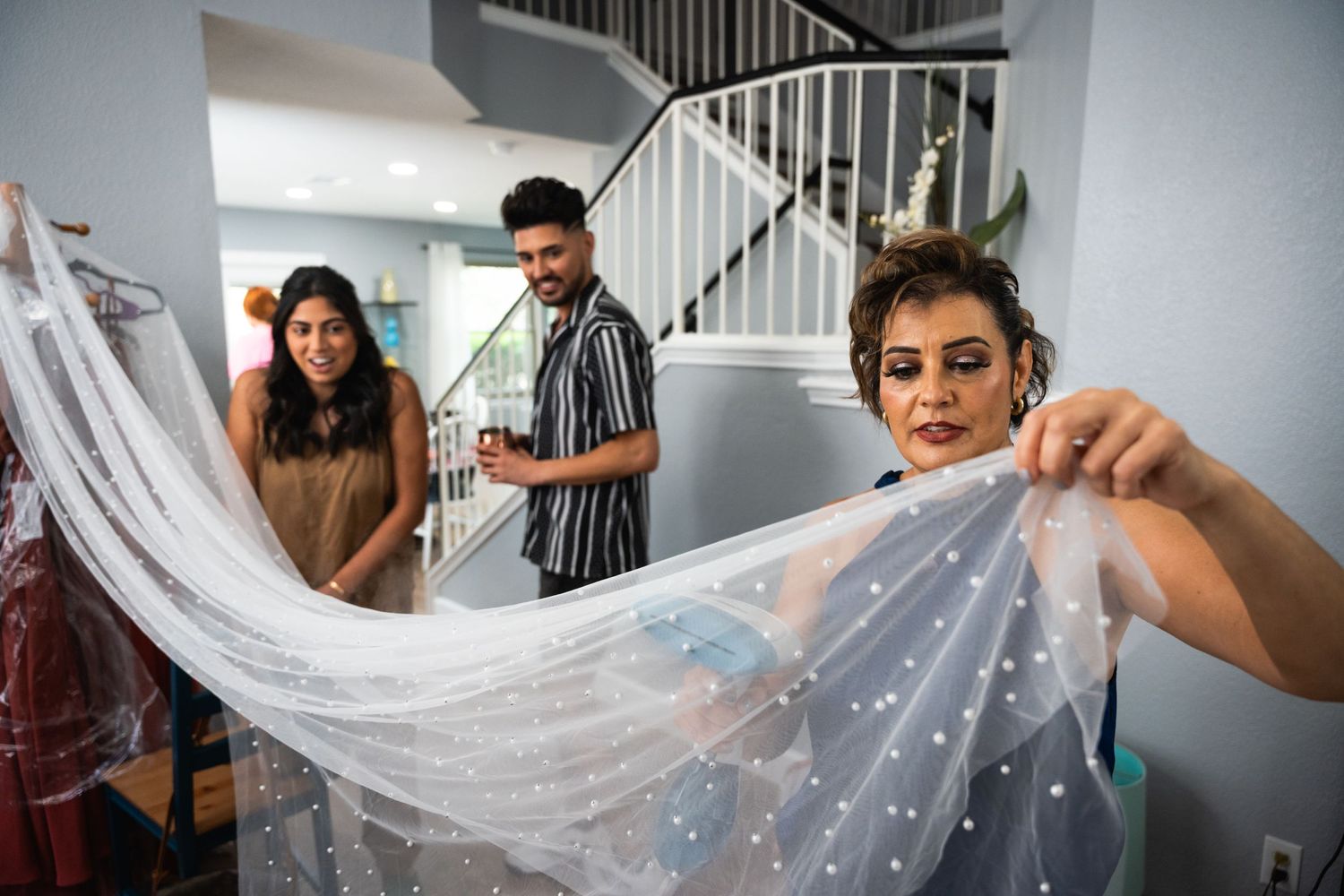 Wedding preparation scene with someone holding a delicate veil in a bright interior space.