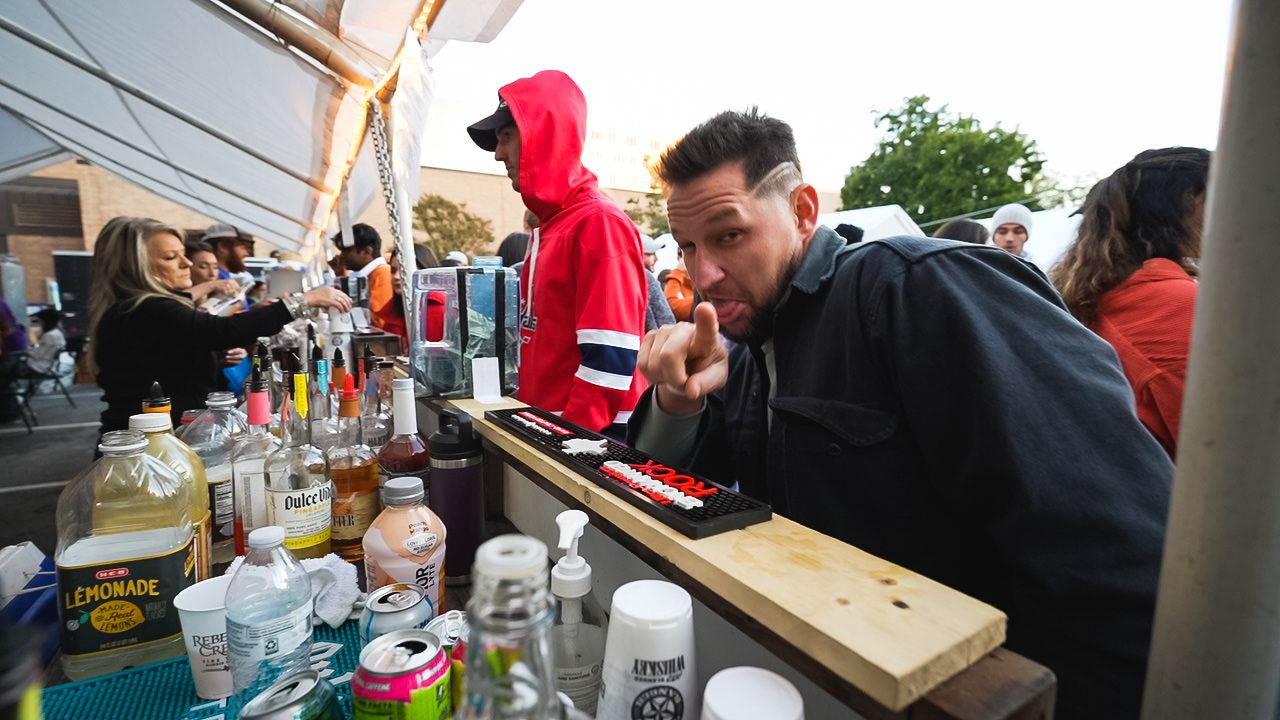 Person leaning over a bar counter at an outdoor event setup.