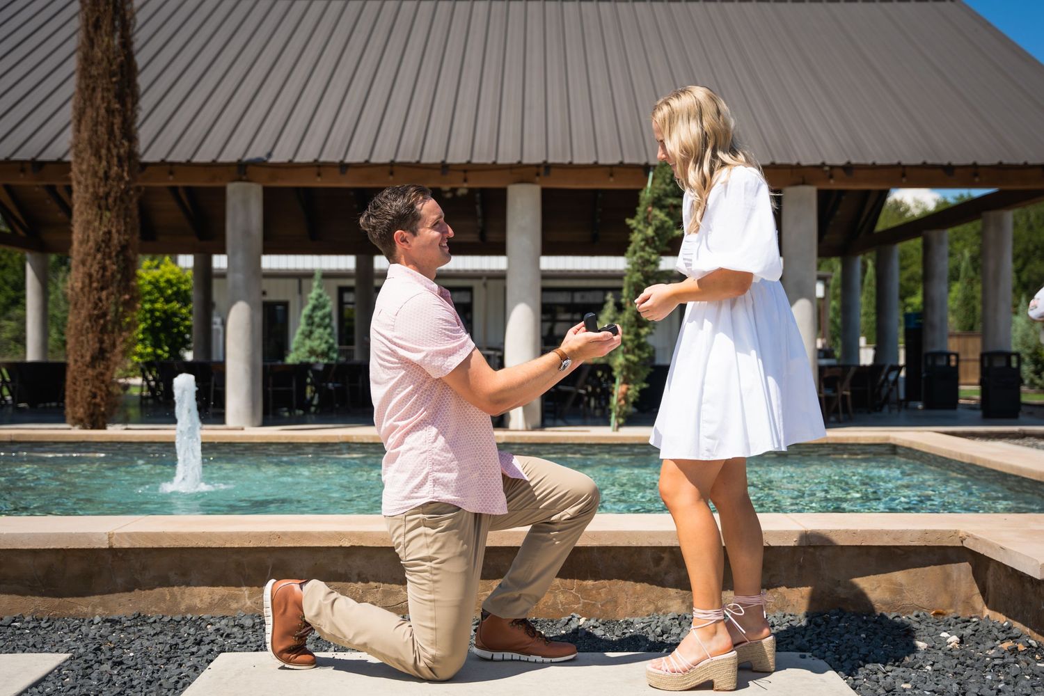 A proposal moment captured by a fountain with a person kneeling.