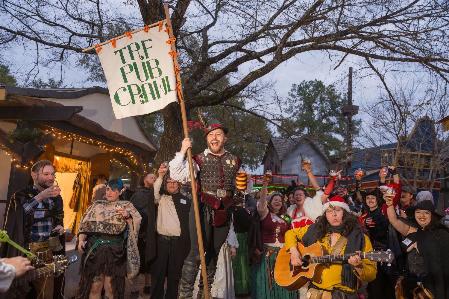 Protesters gather outside at dusk holding illuminated signs and banners during a peaceful demonstration.