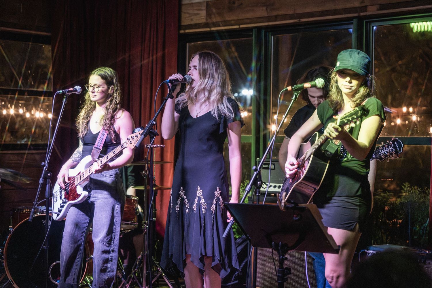 A live band performs on stage in a dimly lit venue with purple and green lighting effects.