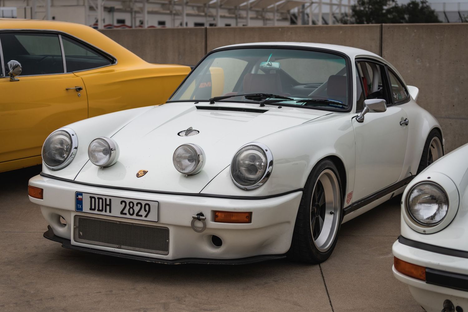 White Porsche 911 with distinctive RSR-style modifications parked at a car show.