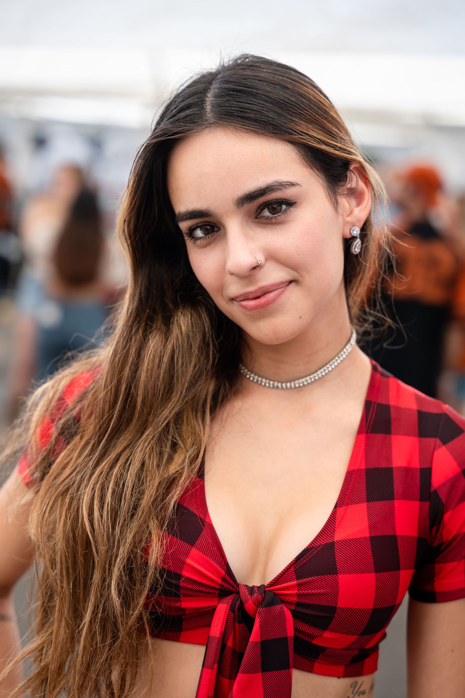 Person wearing red buffalo plaid crop top with choker necklace at outdoor event.