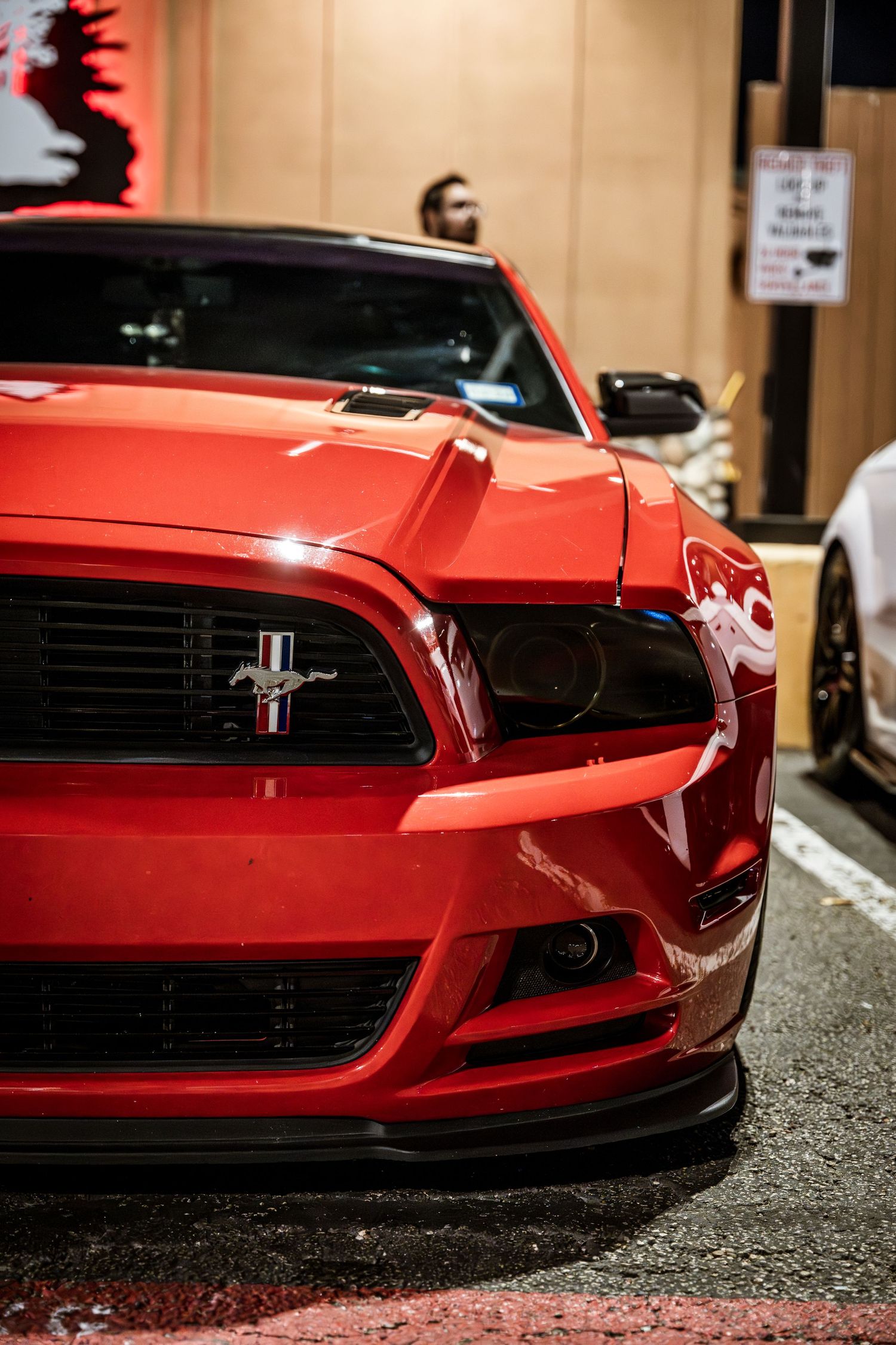 Front end detail of a red Ford Mustang showing aggressive grille and hood design.