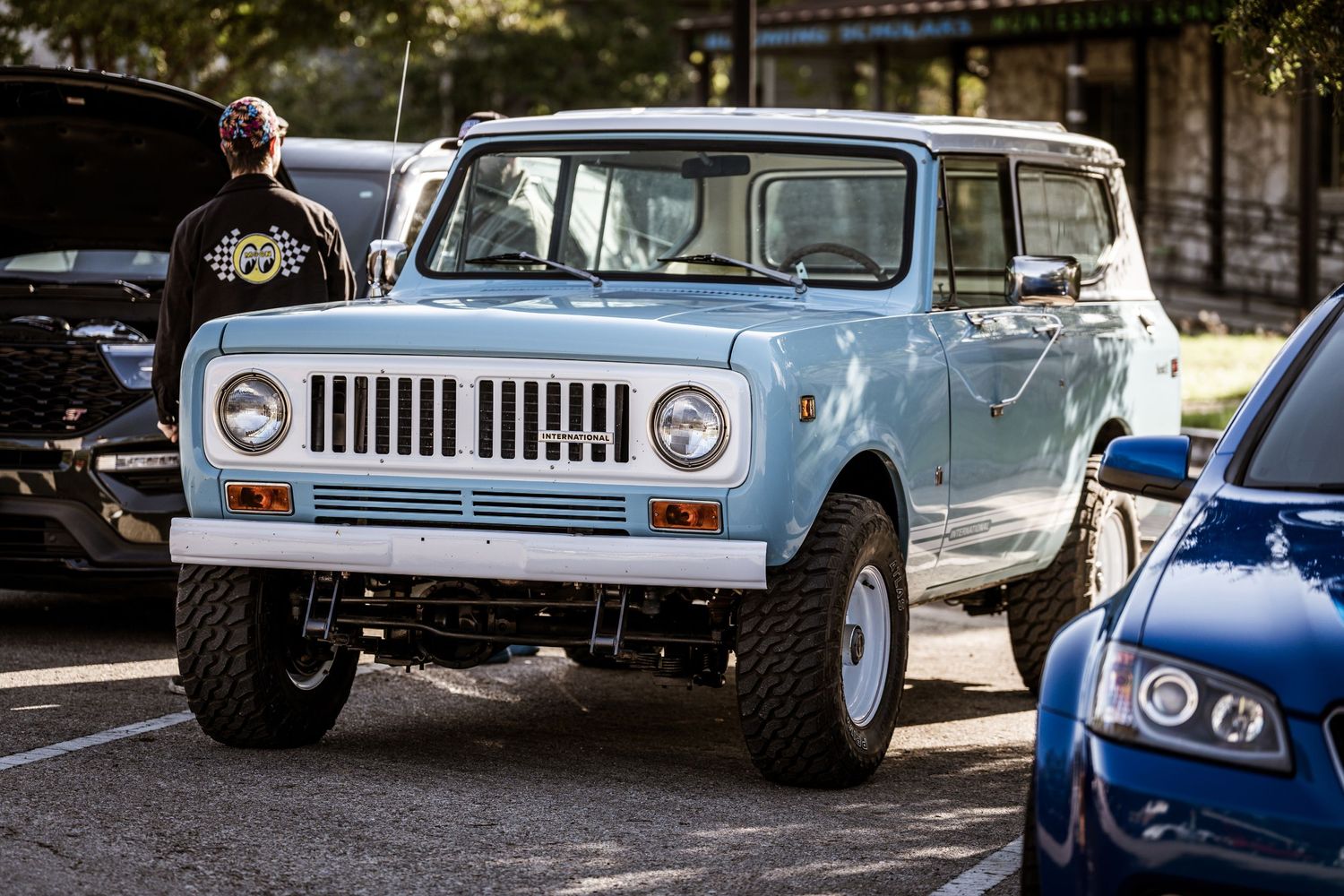 Light blue International Scout SUV with lifted suspension parked on a street corner.