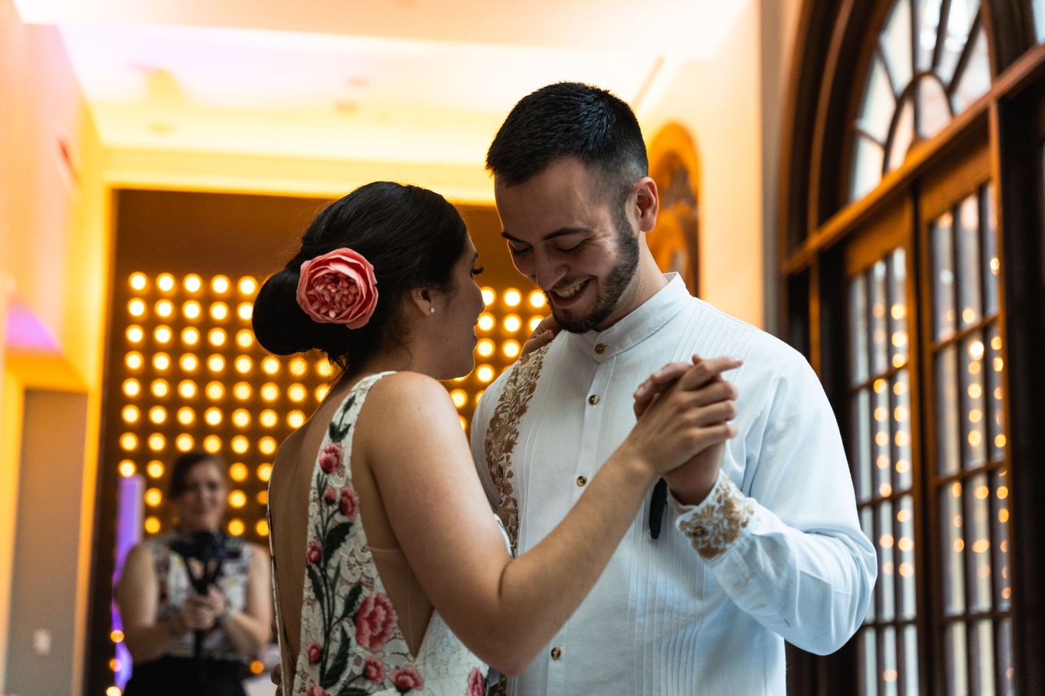 A couple shares an intimate dance moment under warm lighting at an indoor venue.